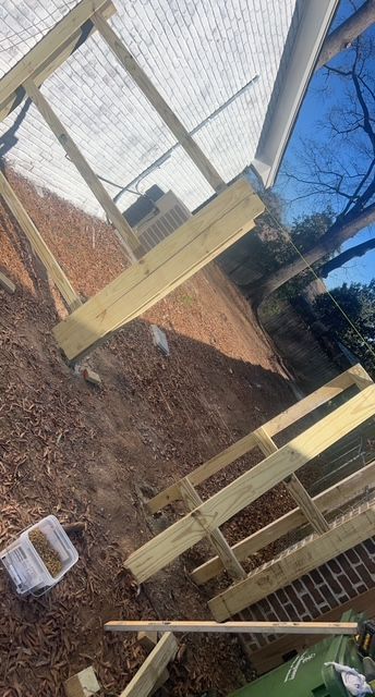 A wooden deck is being built in the backyard of a house.