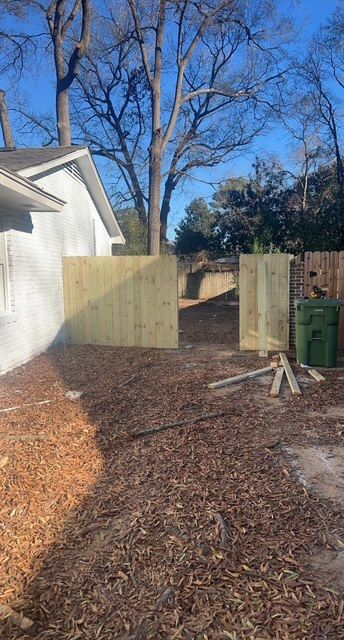 A wooden fence is being built in the backyard of a house.