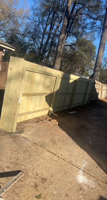 A wooden fence is sitting on top of a concrete driveway.