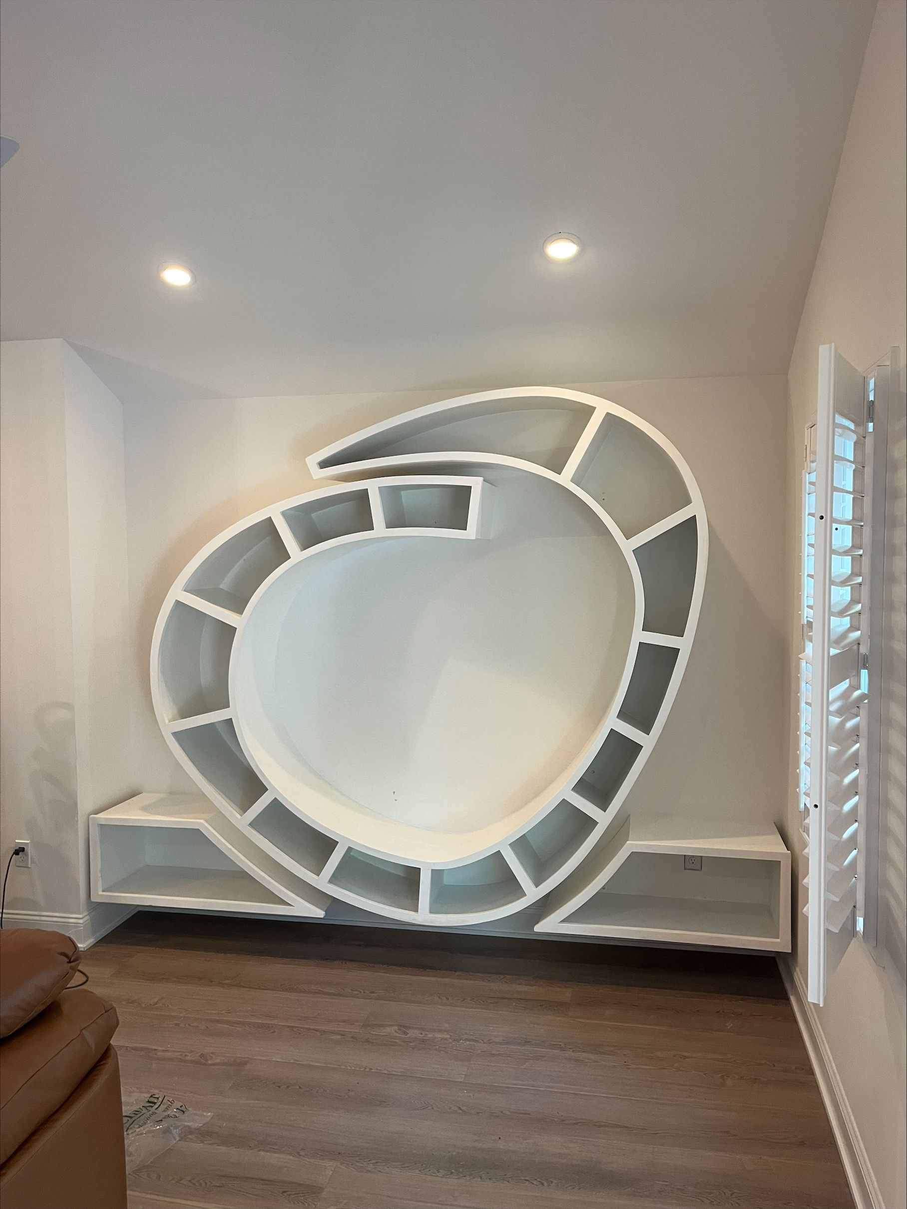 White, circular built-in shelving unit with multiple compartments on a white wall designed and isntalled by cape island woodworks in cape may, new jersey