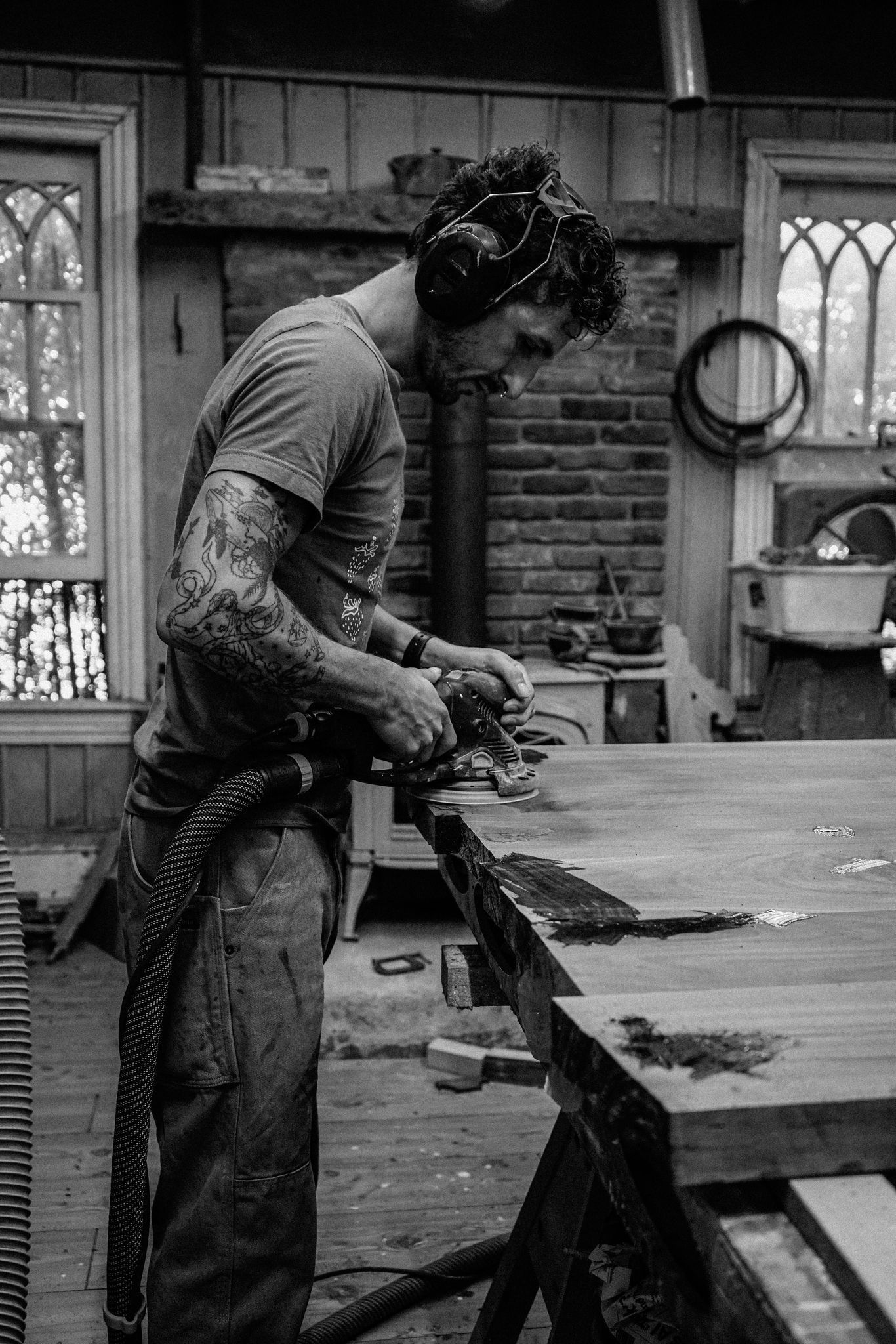 a man is working on a wooden table in a black and white photo .