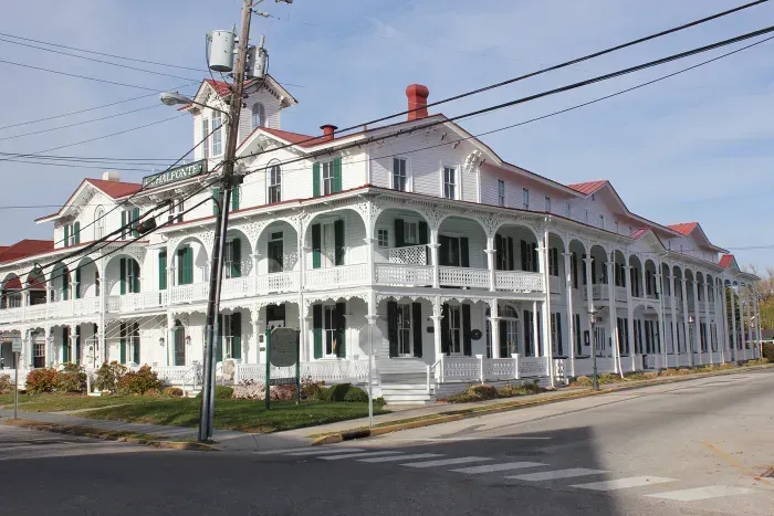 a large white building with a red roof sits on the corner of a street in cape may, new jersey