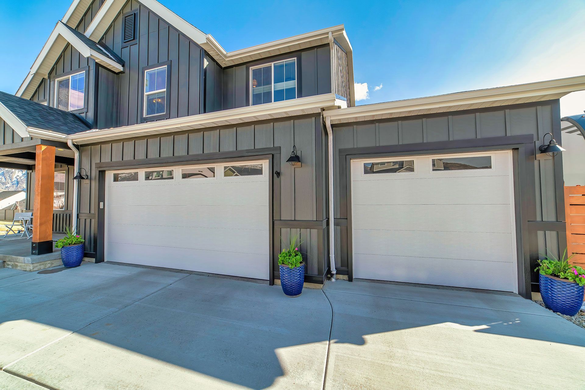 Two car attached garage and open porch at home facade against sunny blue sky 