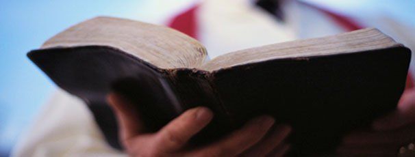 A person is holding an open bible in their hands.