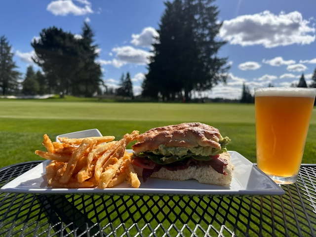A sandwich and fries on a plate next to a glass of beer.