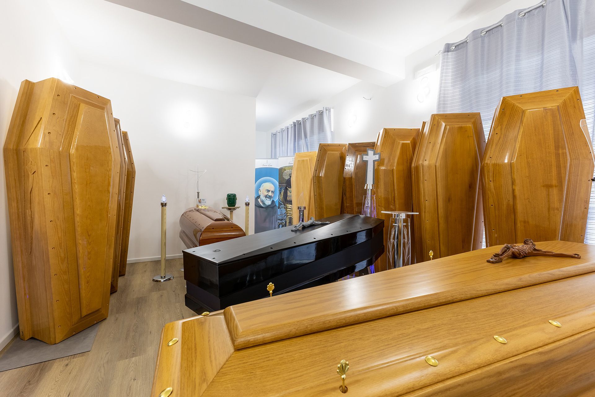 Una stanza in cui sono esposte numerose bare di legno di varie dimensioni e finiture.