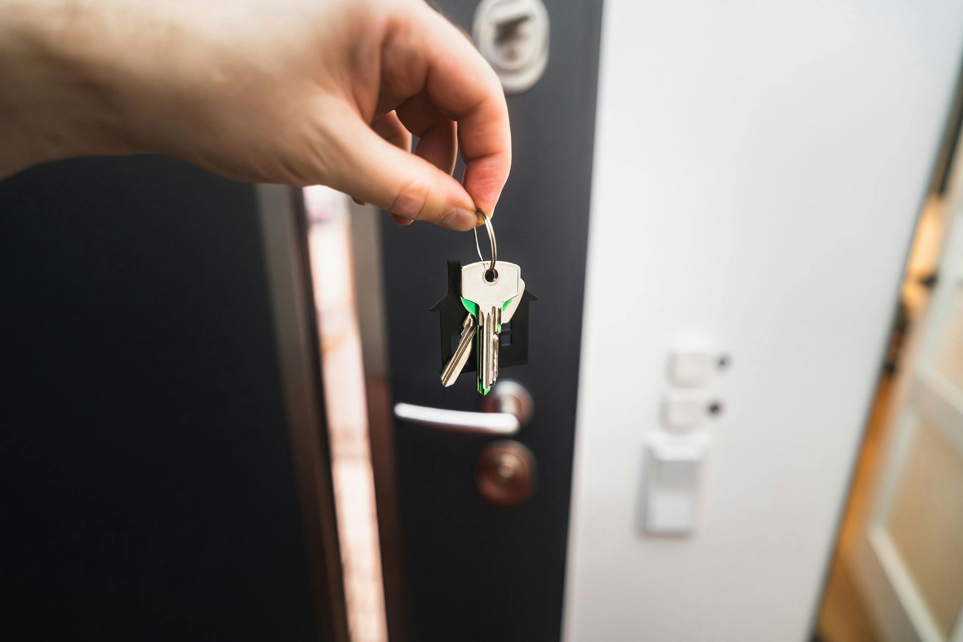 A person is holding a pair of keys in front of a door.