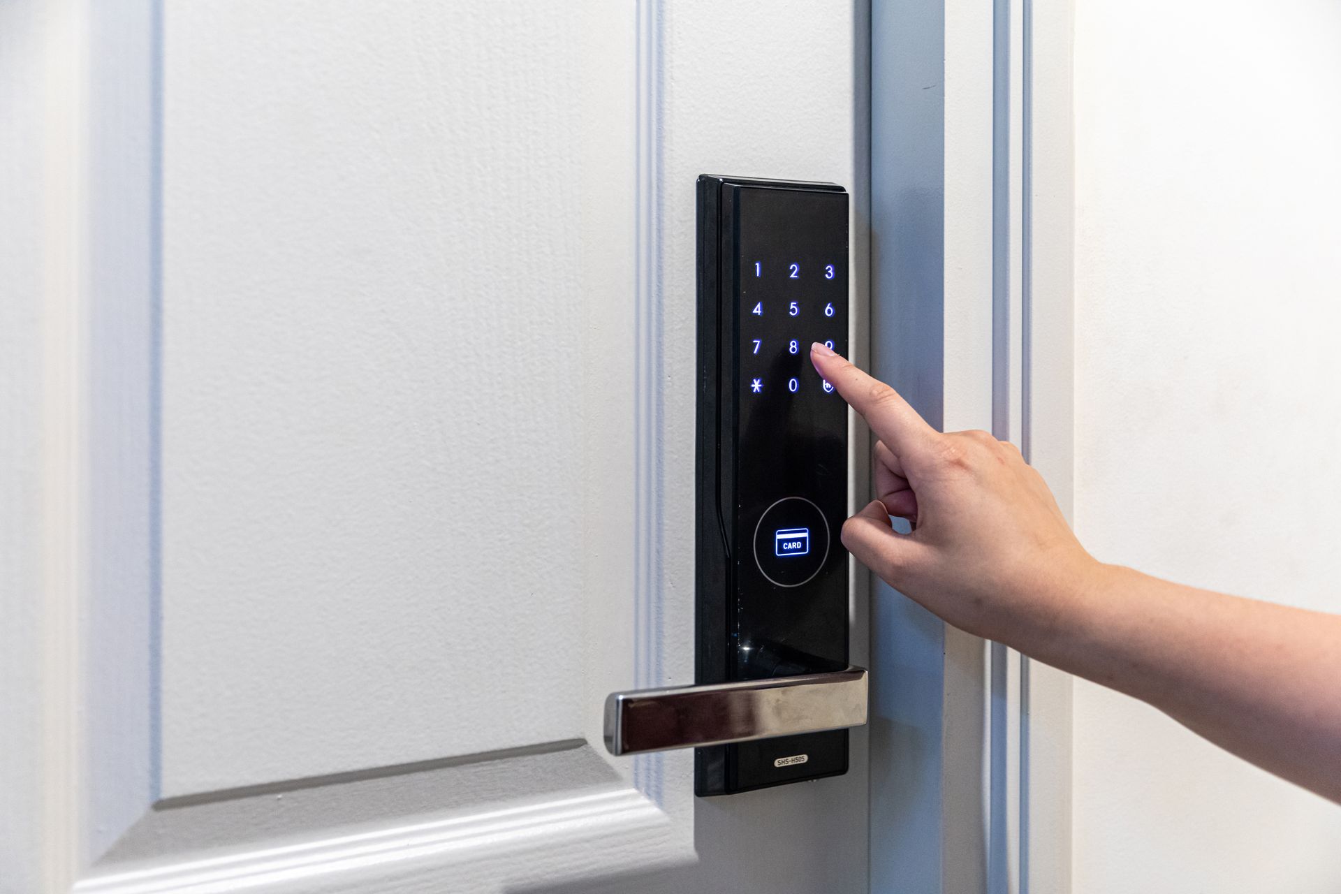 A person is pressing a button on a door lock.