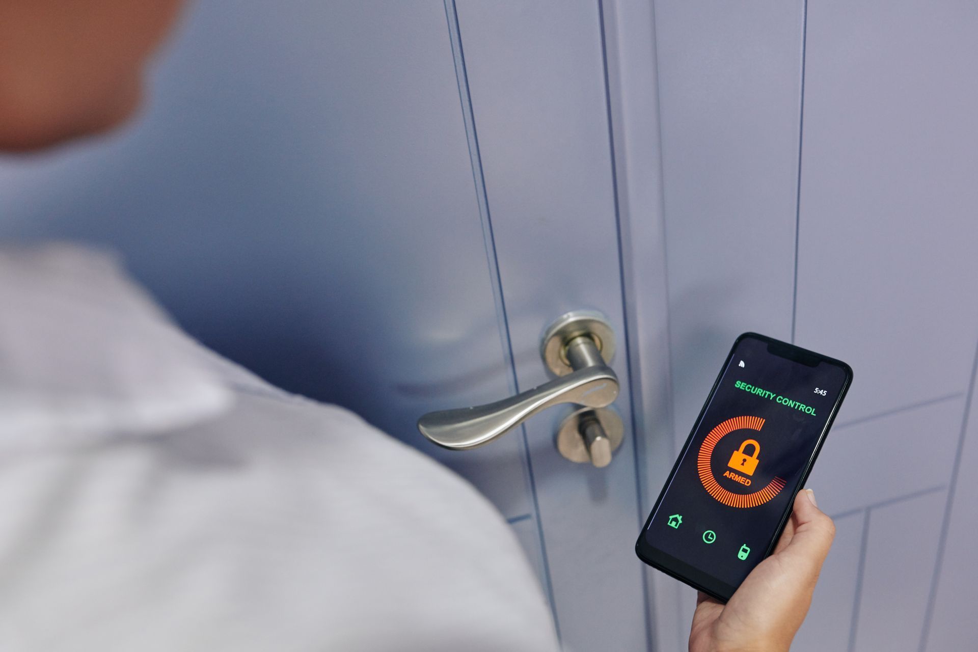 A person is holding a cell phone in front of a door.
