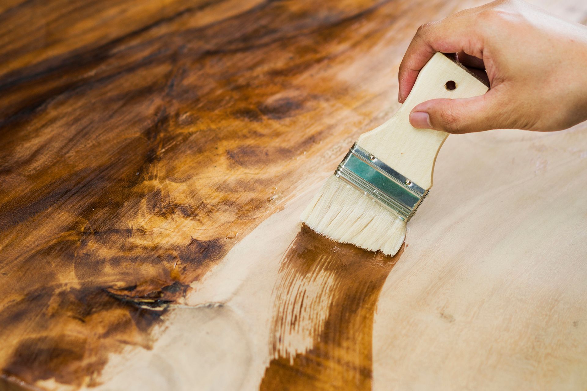 A person is painting a piece of wood with a brush.