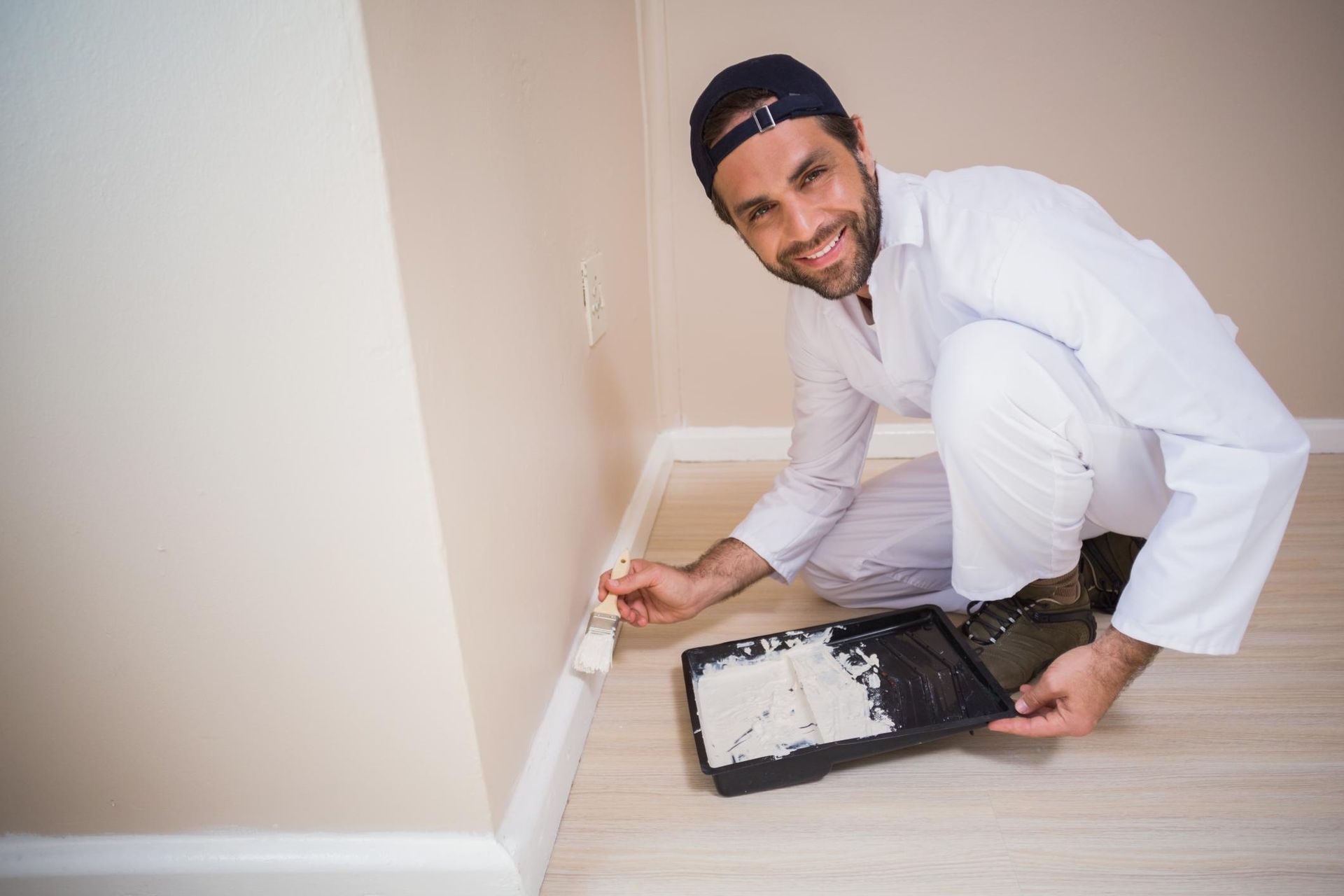 a man kneeling on the floor painting a wall