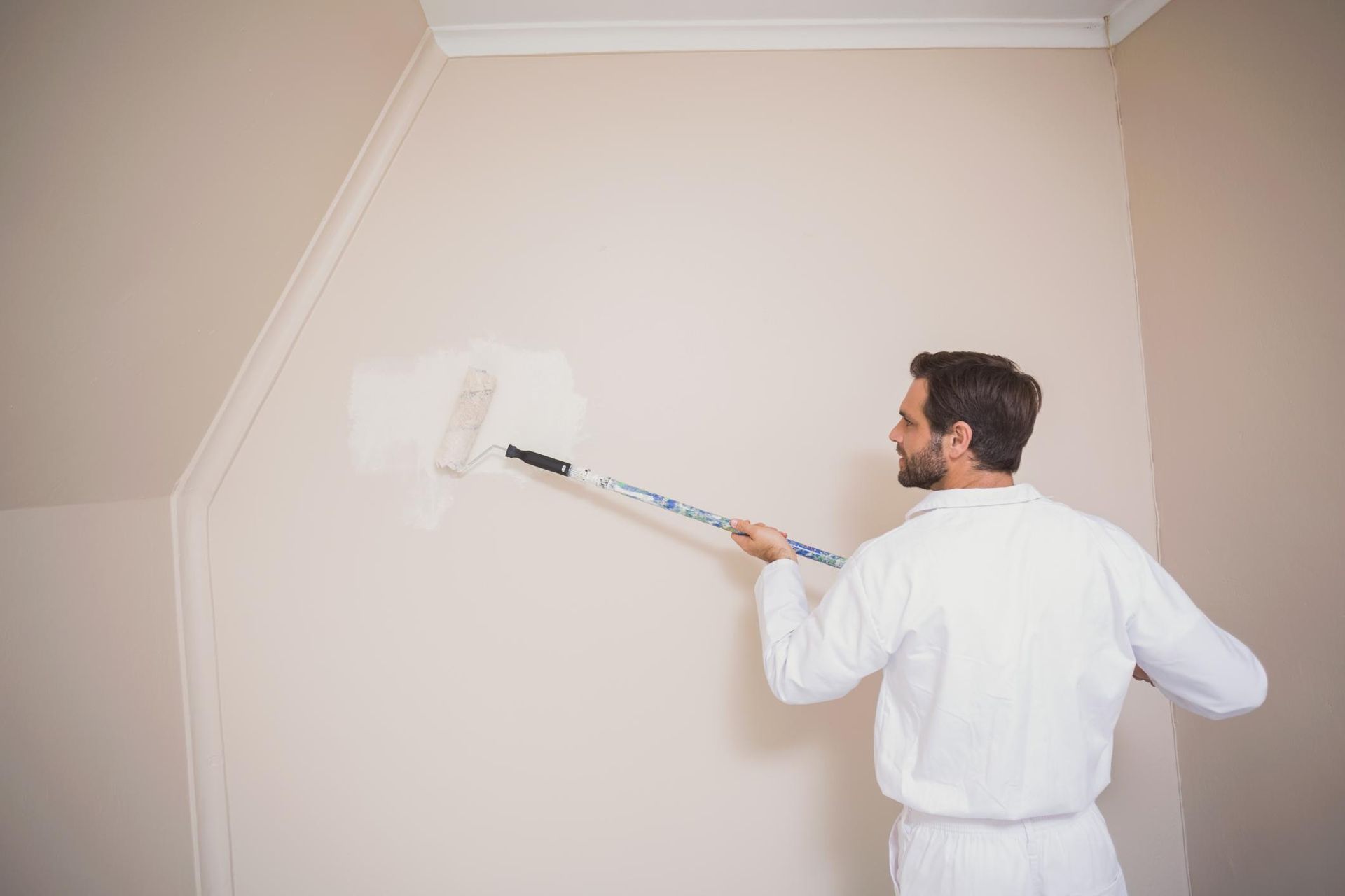 a man painting a wall with a paint roller