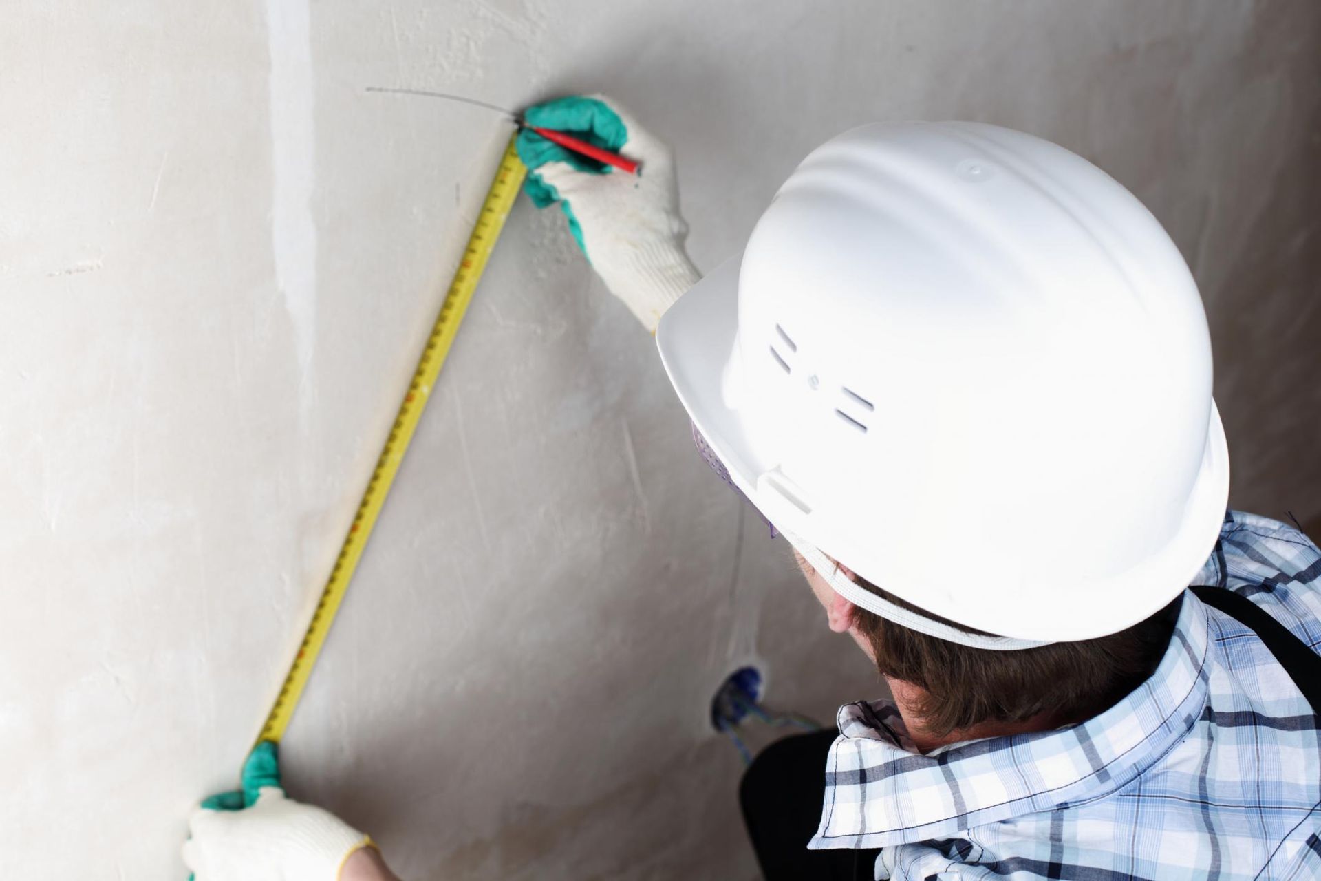 a man wearing a hard hat and holding a measuring tape