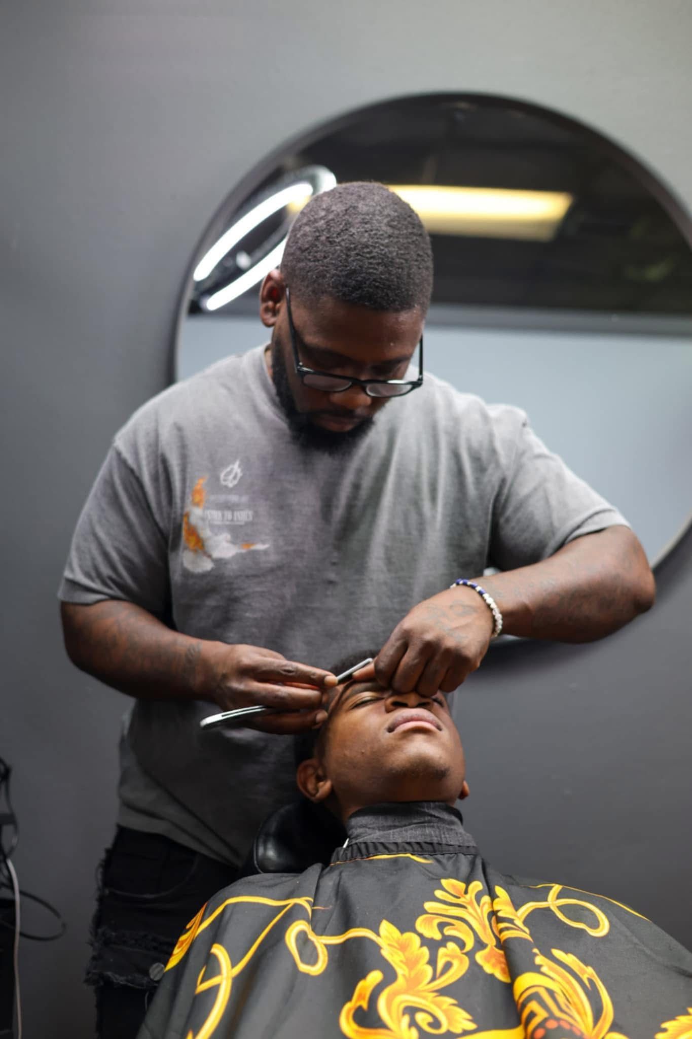 Barber trimming client's eyebrows with scissors; salon setting.