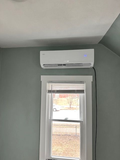A room with a window and a wall mounted air conditioner.