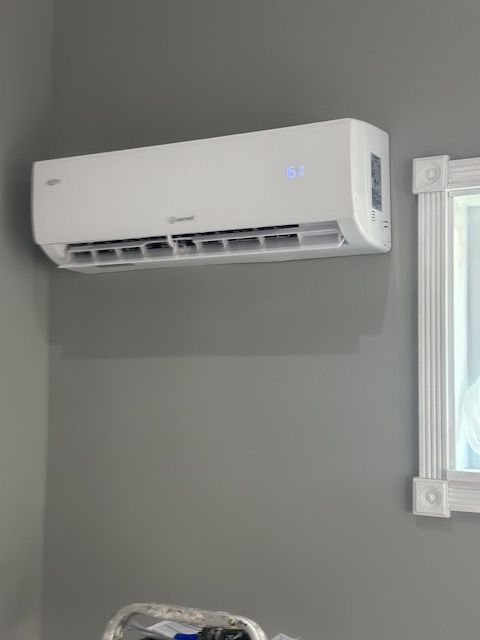 A white air conditioner is hanging on a wall next to a mirror.