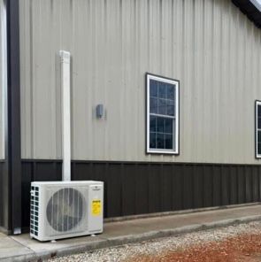 A white air conditioner is sitting on the side of a building next to a window.