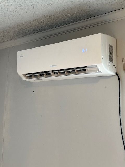A white air conditioner is hanging on a white wall.