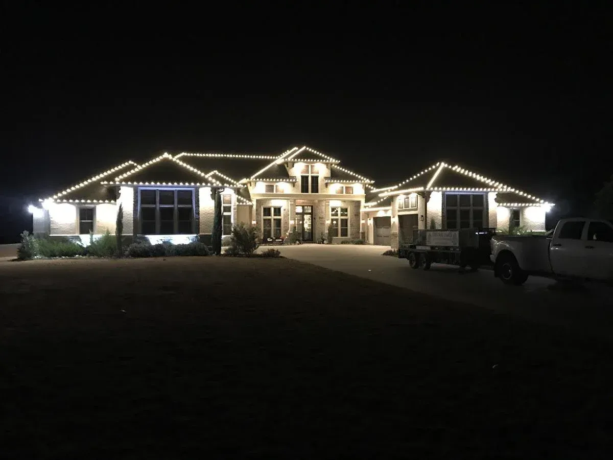 Large house illuminated with white Christmas lights at night.
