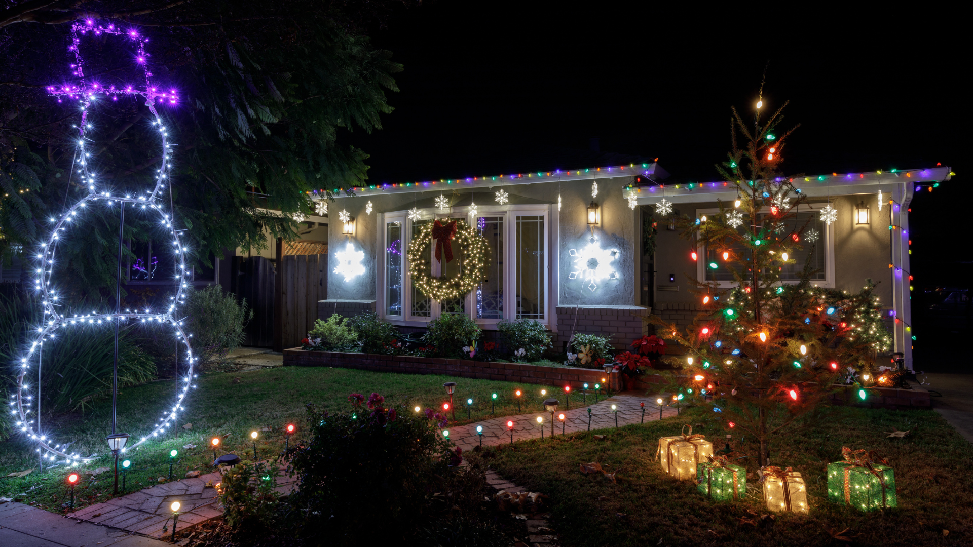 House decorated for Christmas with a lit-up snowman, tree, and lights.