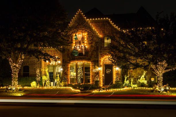 House decorated with bright yellow Christmas lights at night. Trees and lawn also lit.