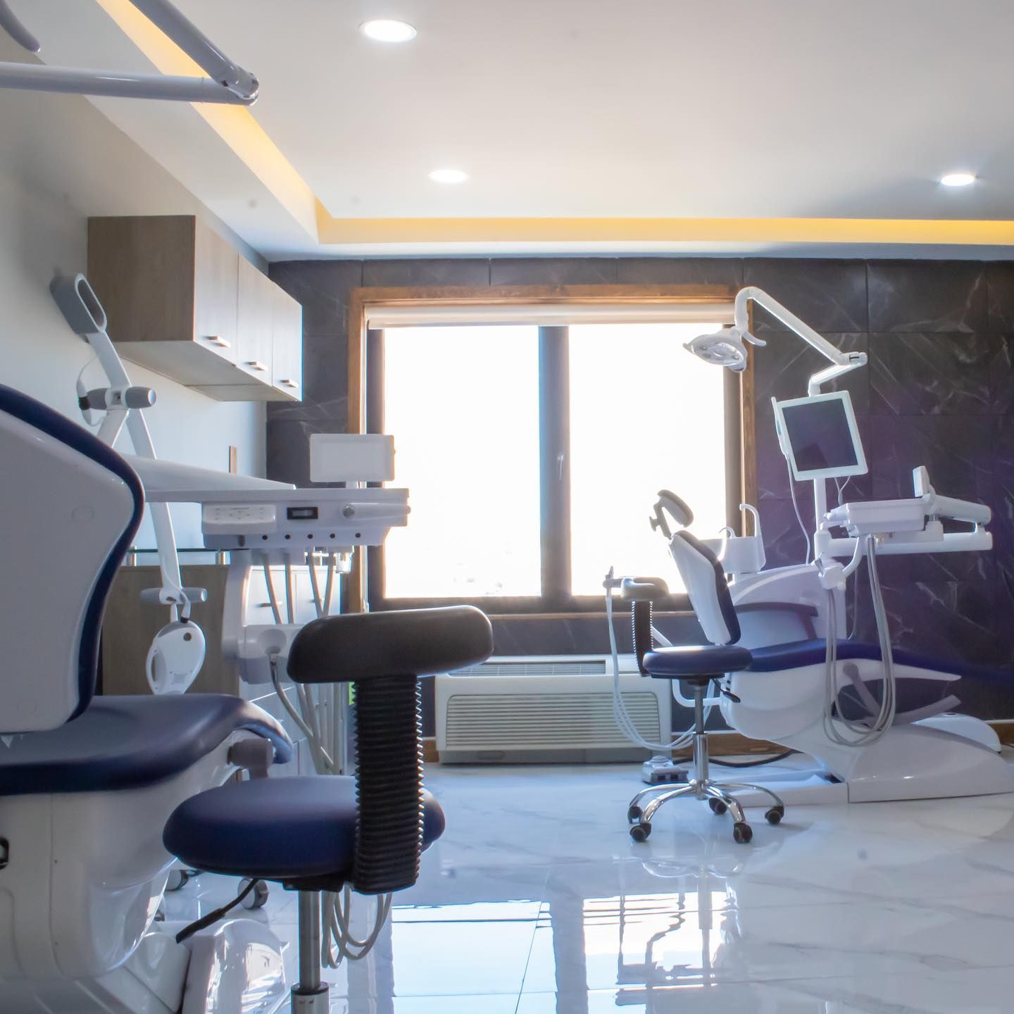 Un consultorio dental con dos sillas y una ventana.