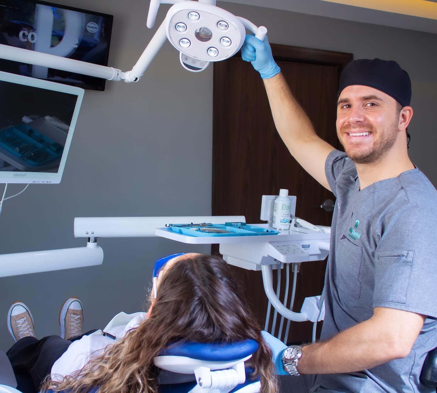 Un dentista sostiene una luz sobre un paciente en un sillón dental.
