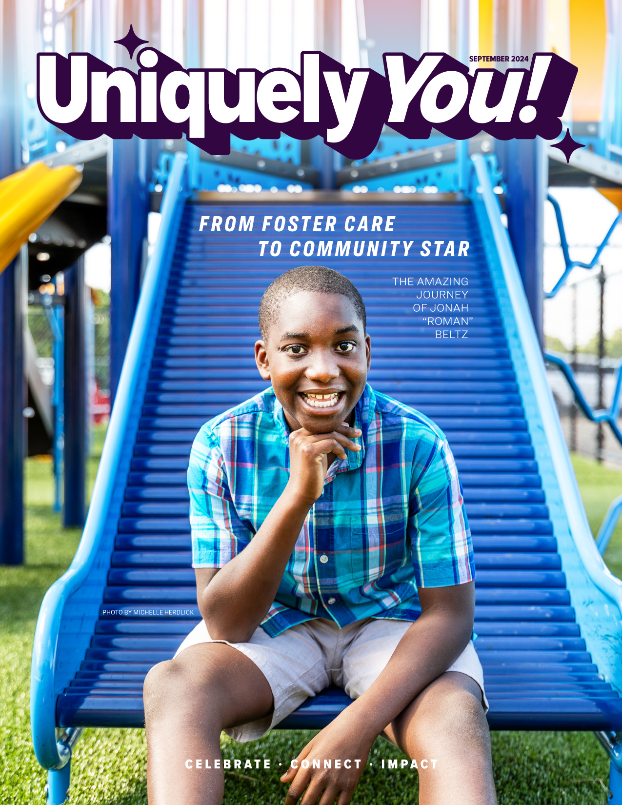 A young boy is sitting on a blue slide at a playground.