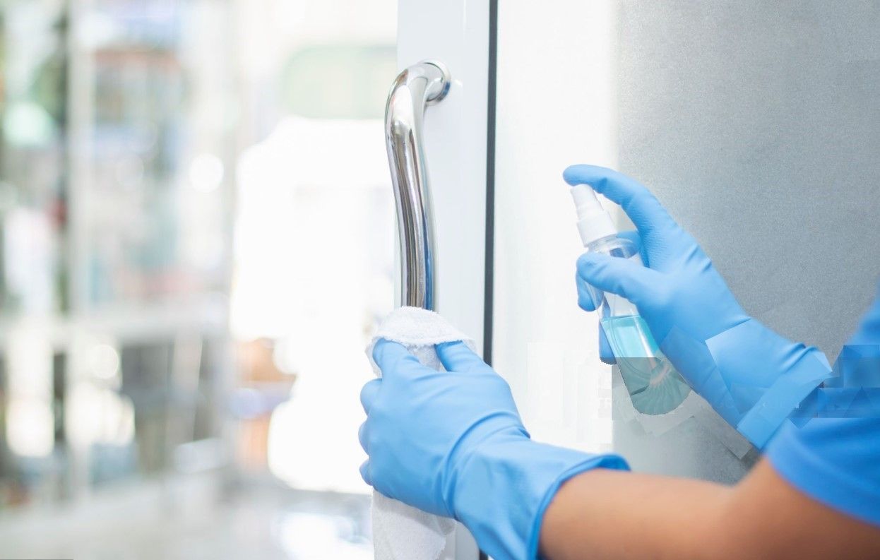 Person disinfecting a glass door