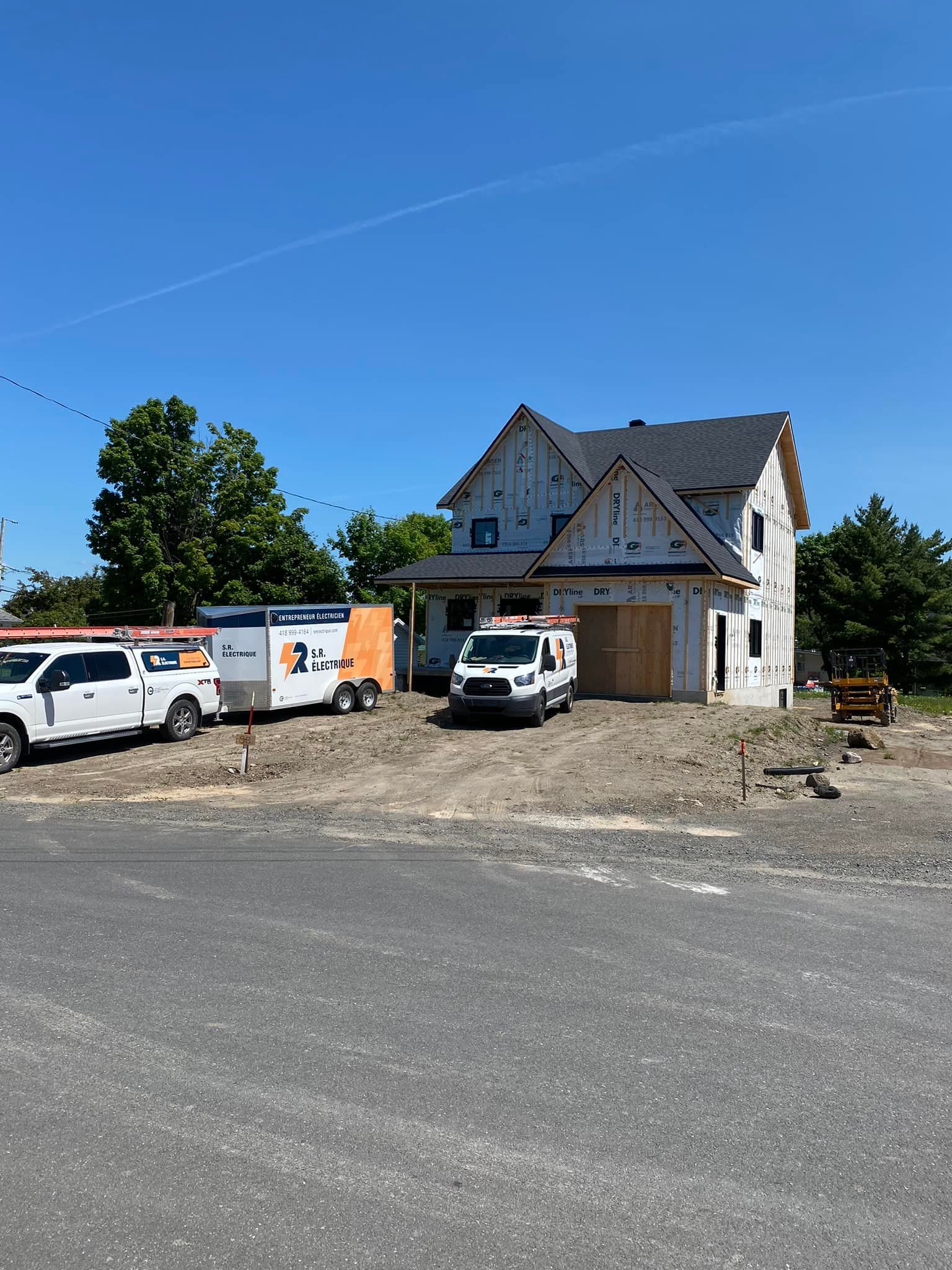 Une maison en construction avec des camions garés devant.