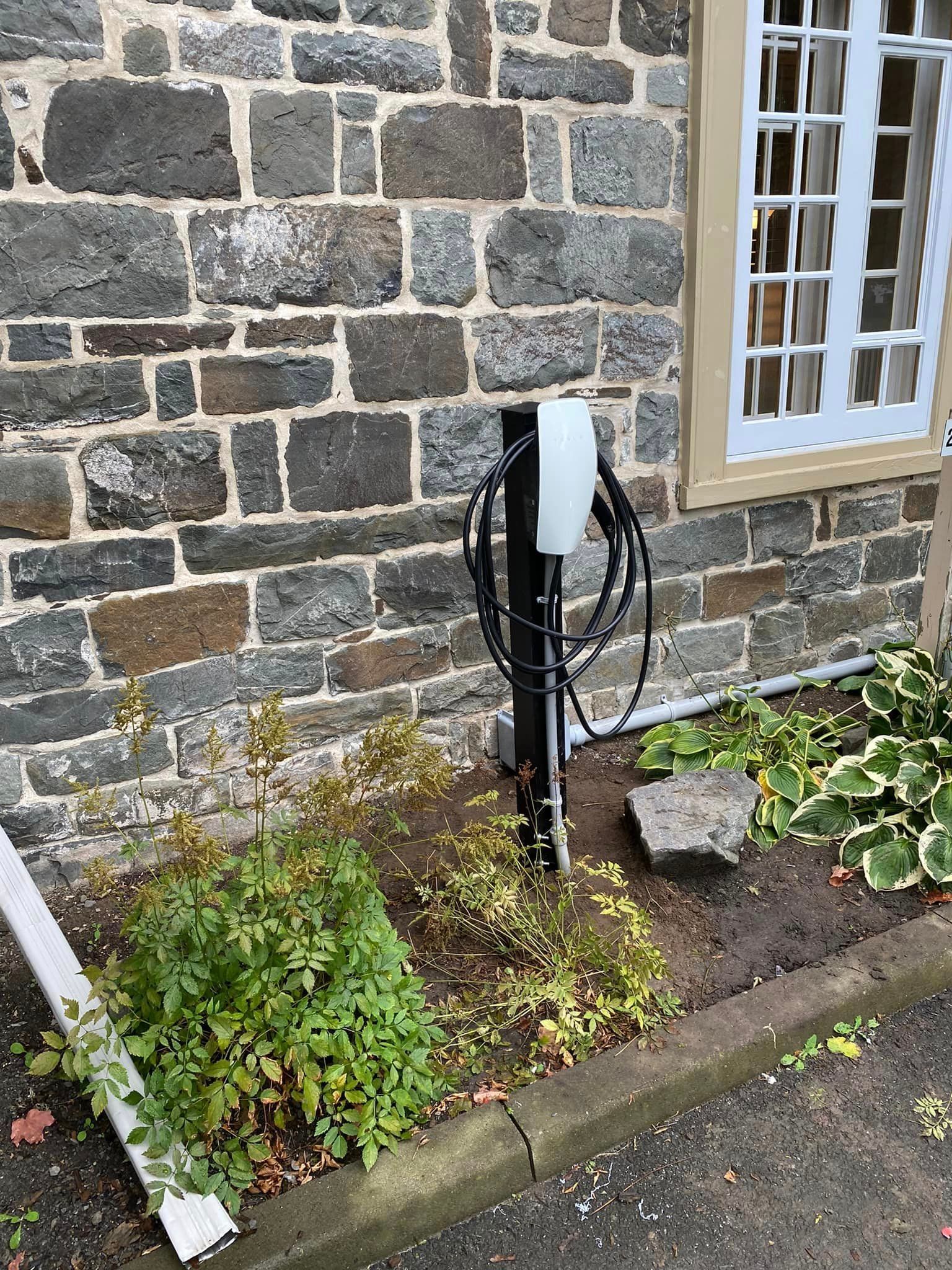 Salle de bains avec baignoire blanche, douche en marbre gris et porte ouverte sur un couloir avec parquet.