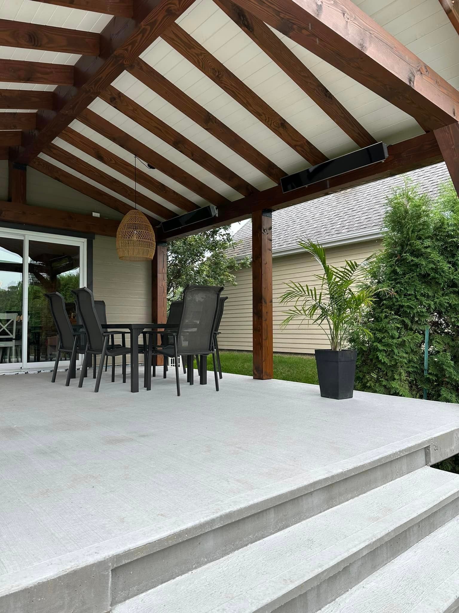 Un patio avec table et chaises sous un toit en bois.