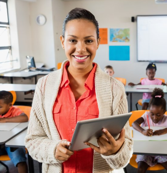 female teacher in classroom holding tablet