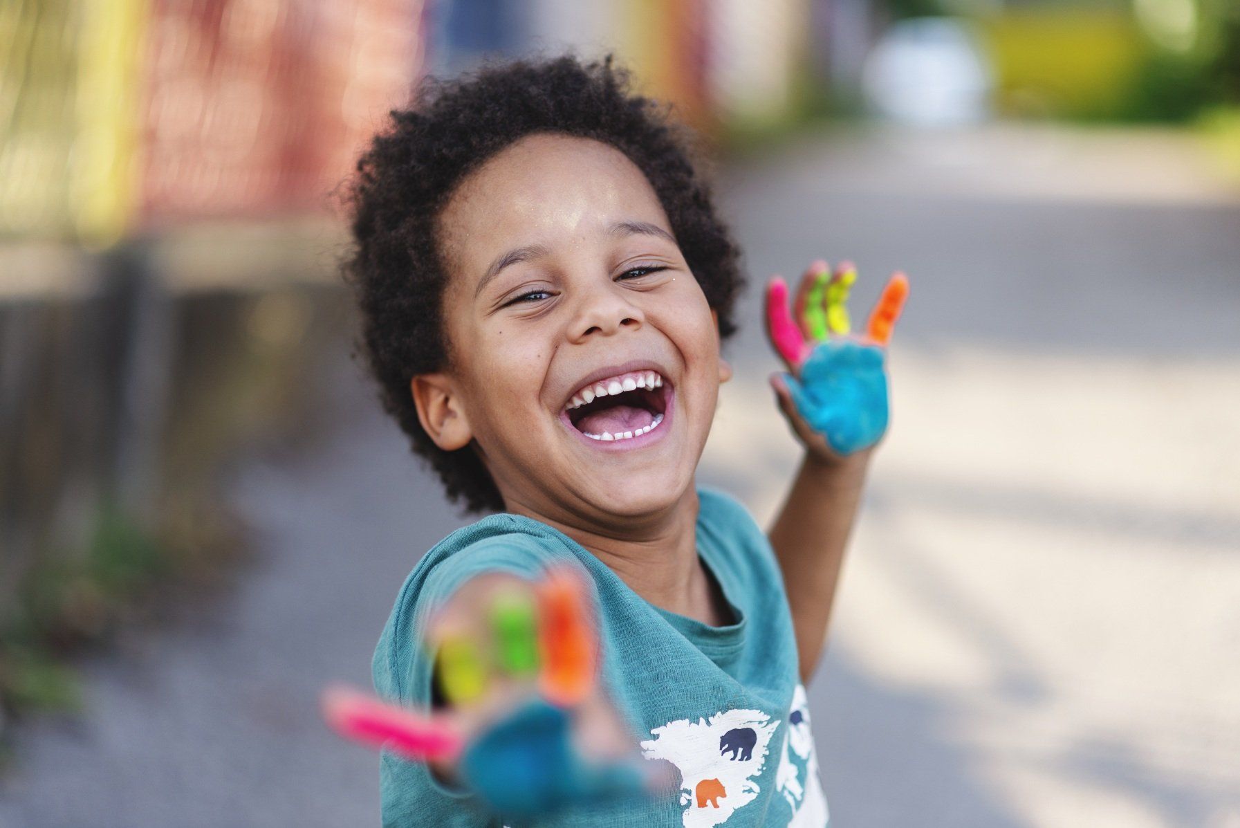 happy toddler with multicolor paint on hands