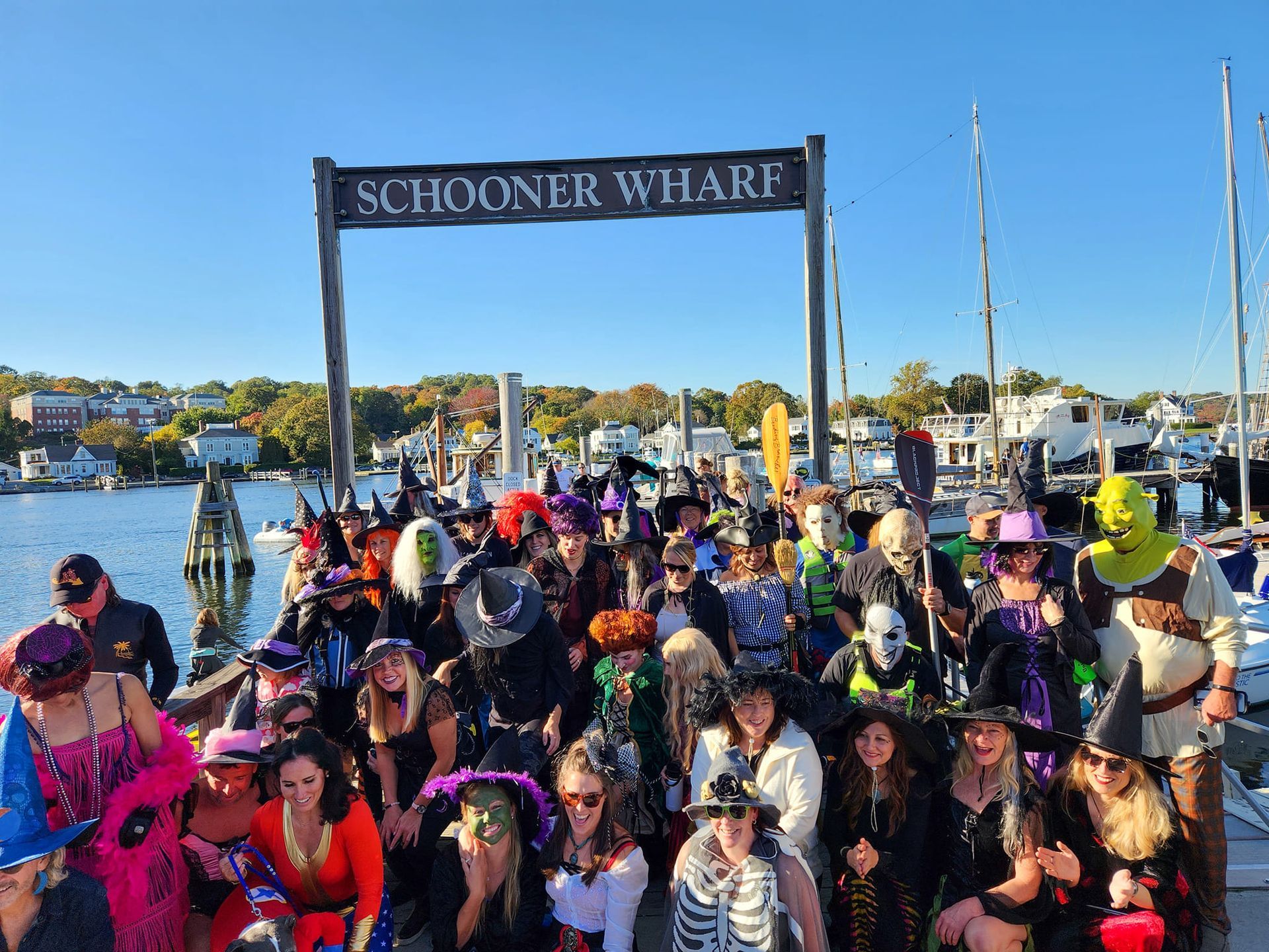A group of people dressed in halloween costumes are standing under a sign that says schooner wilart.