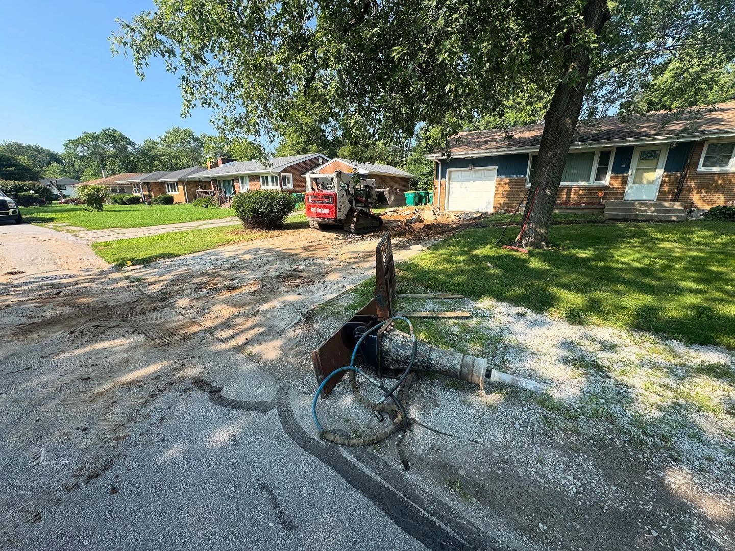 Construction site: Backhoe near residential homes. Debris on ground. Bright, sunny day.