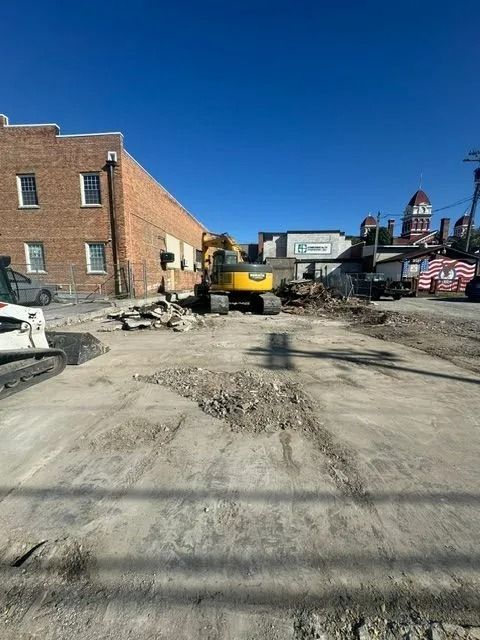 Construction site with an excavator demolishing a building; brick building, blue sky.