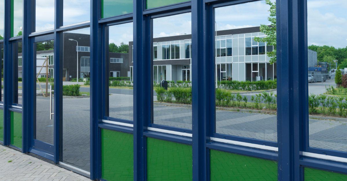 The front of a building with all of the windows tinted; the windows are reflecting the buildings across the street.