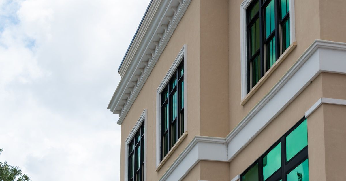 A pale yellow home's exterior with white decorative trim and molding; the windows have a dark blue t