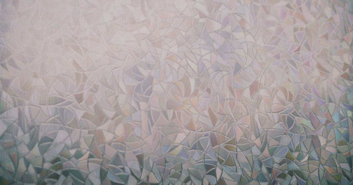 A close-up of decorative privacy window film featuring an abstract pattern resembling stained glass.