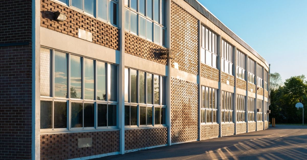 A close-up of a shattered window with a central impact point, surrounded by radiating cracks across the glass surface.