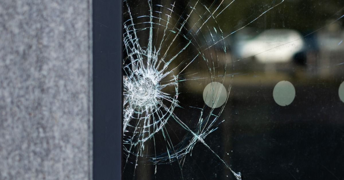 A large brick school building with rows of tall windows lines a paved area, lit by warm sunlight and long shadows.