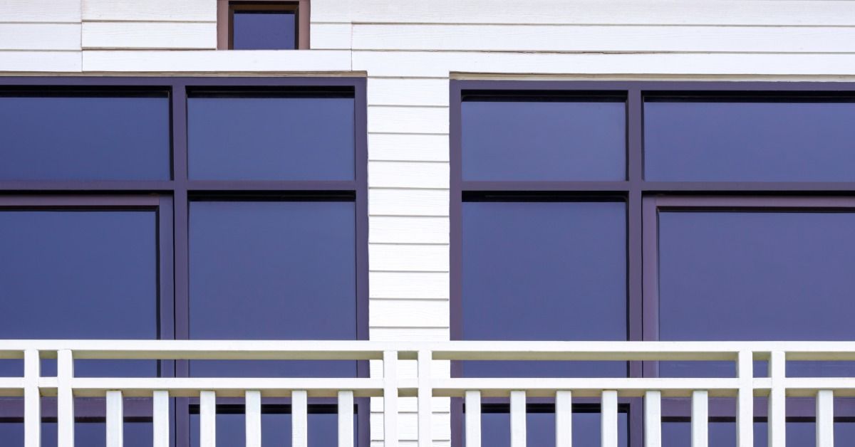A close-up of a home's raised deck outside of the glass windows and doors. The windows and doors have tint.