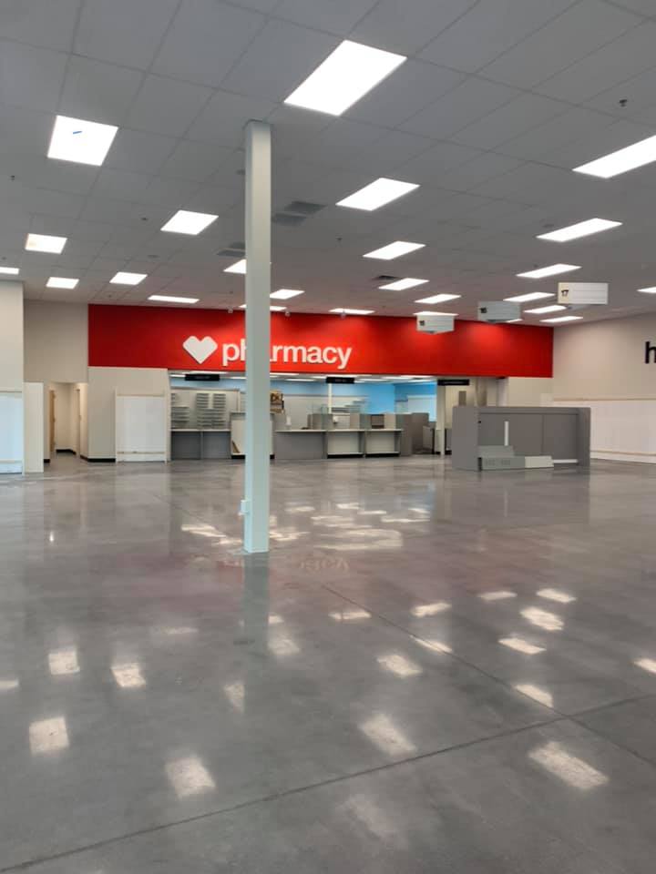 Empty, bright retail space with a red pharmacy sign. Concrete floor, overhead lights, white pillar.