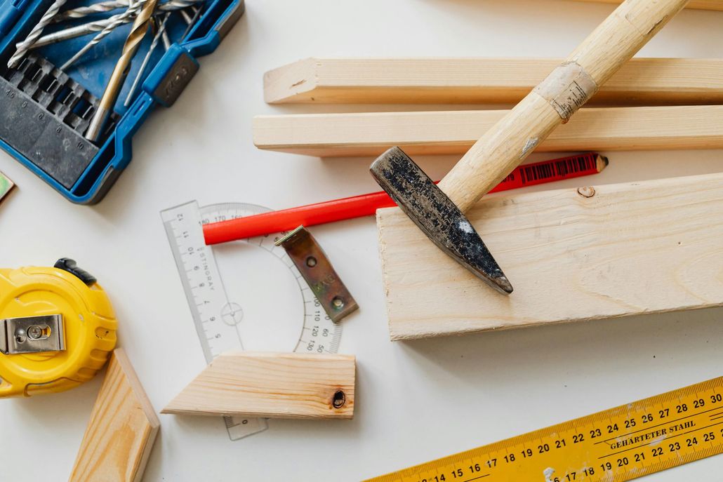 Carpentry hand tools and wood supplies on a white surface.