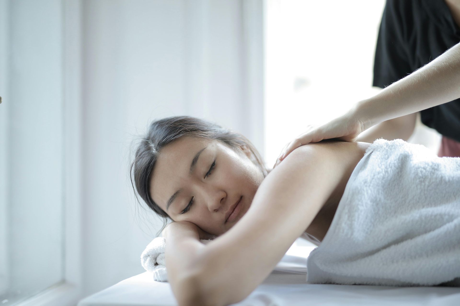 A woman is laying on a bed getting a massage.