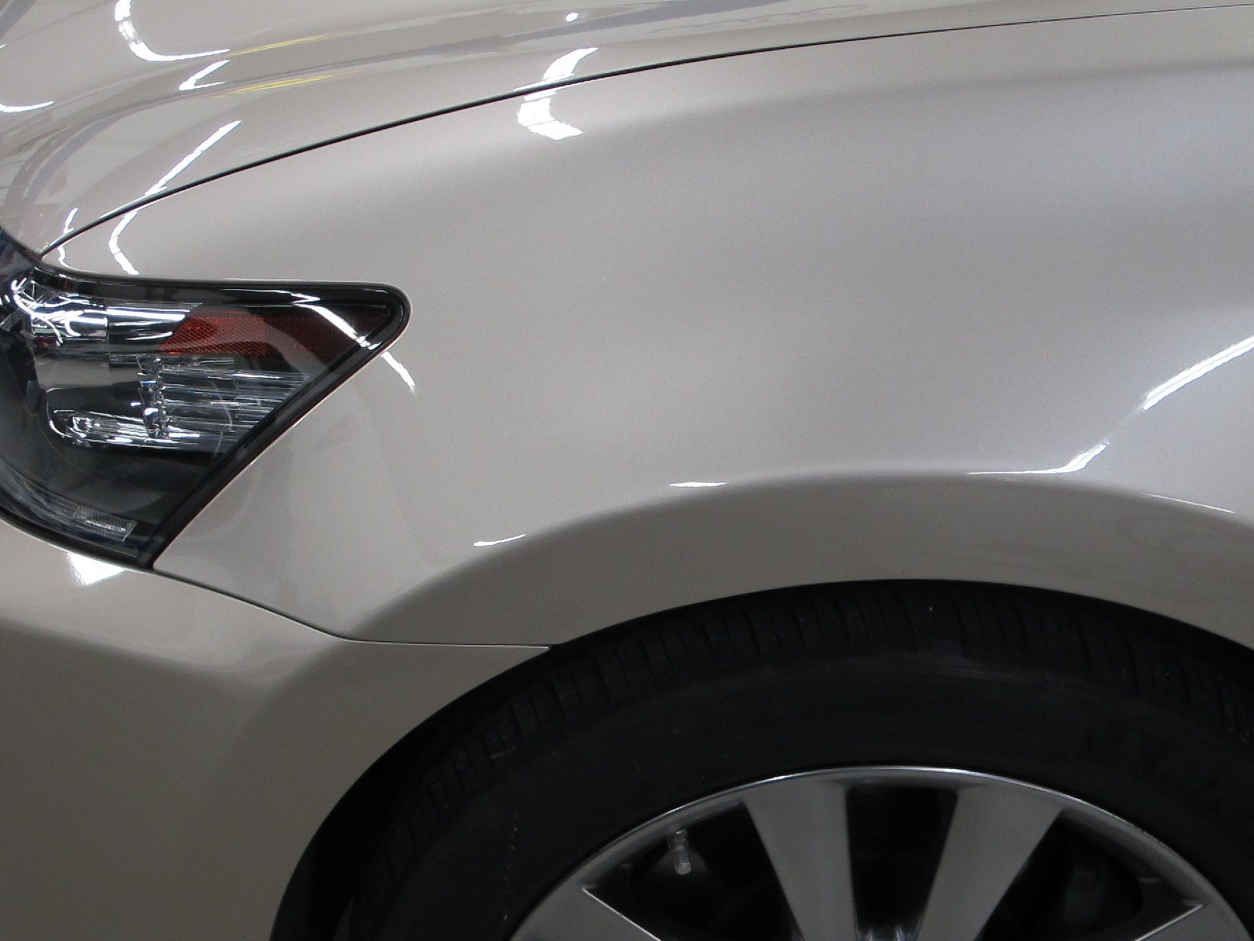 A close up of a white car 's headlight and wheel