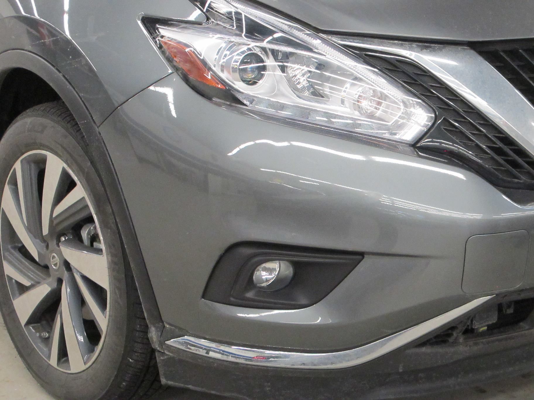 A gray nissan murano is parked in a garage.