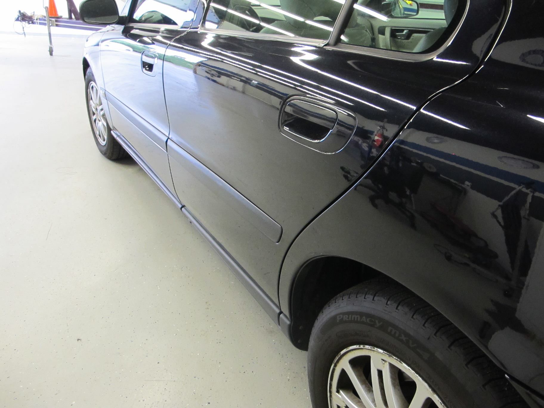 A black car is parked in a garage with the door open