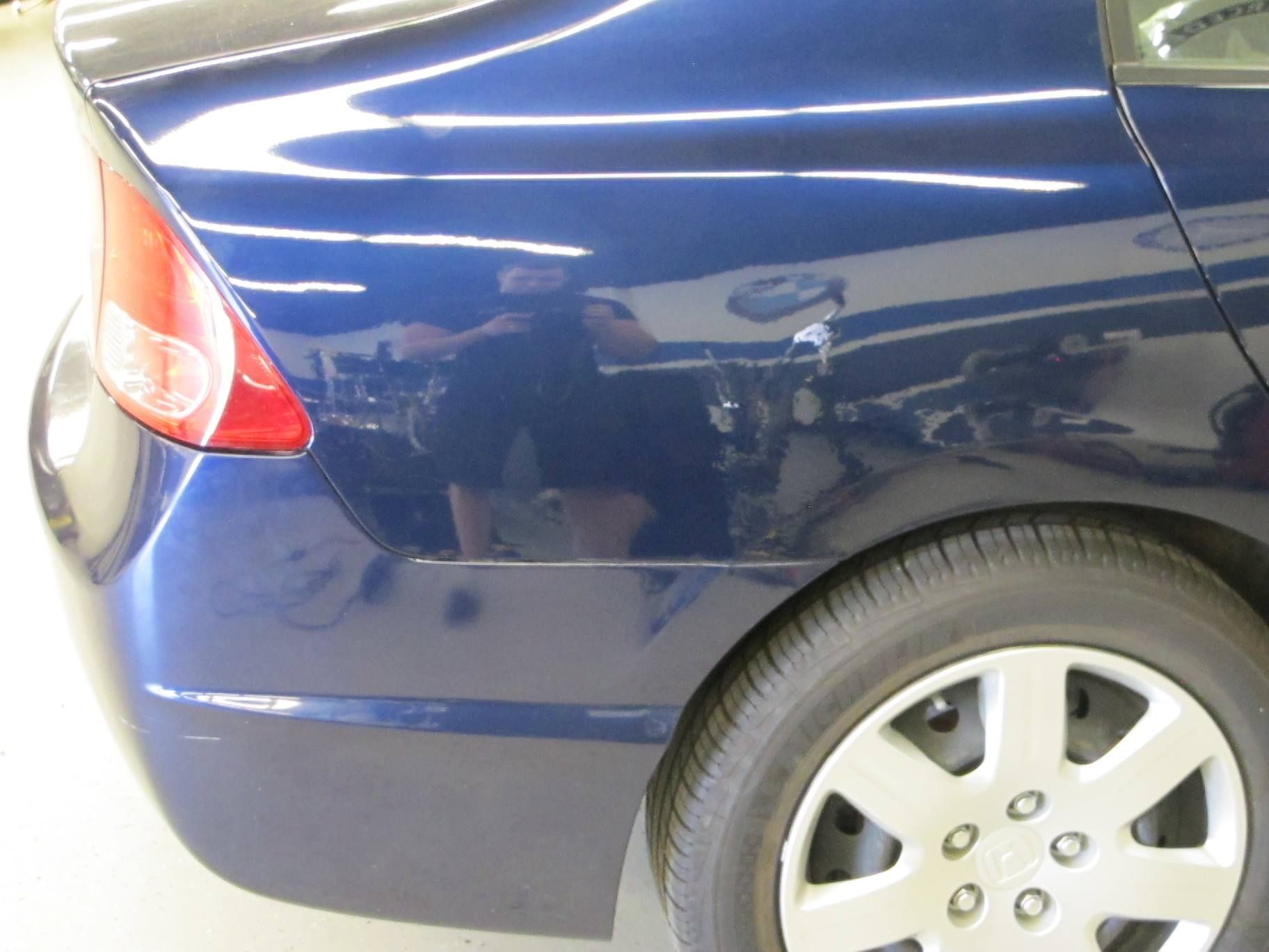 A blue car with silver wheels is parked in a garage